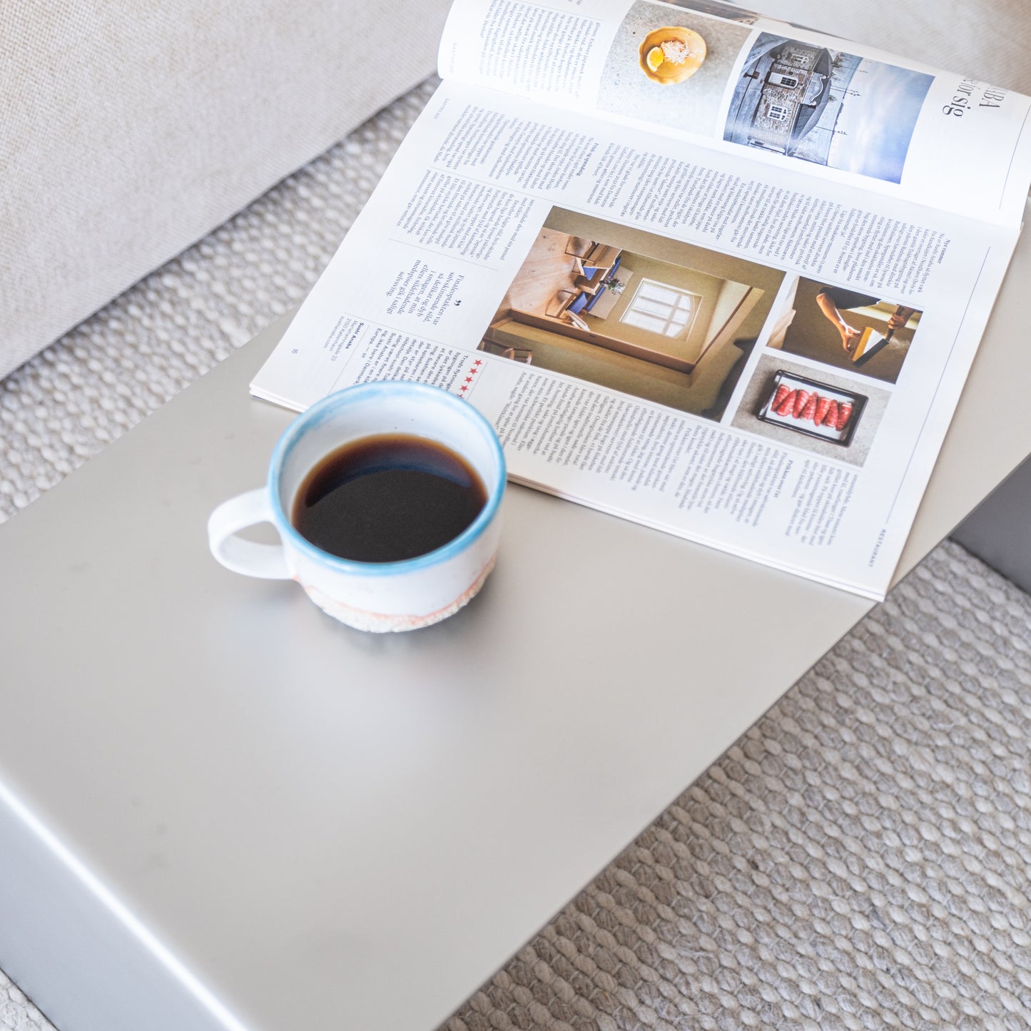 Elegance Side Table positioned lengthwise with magazines and a coffee cup on top.